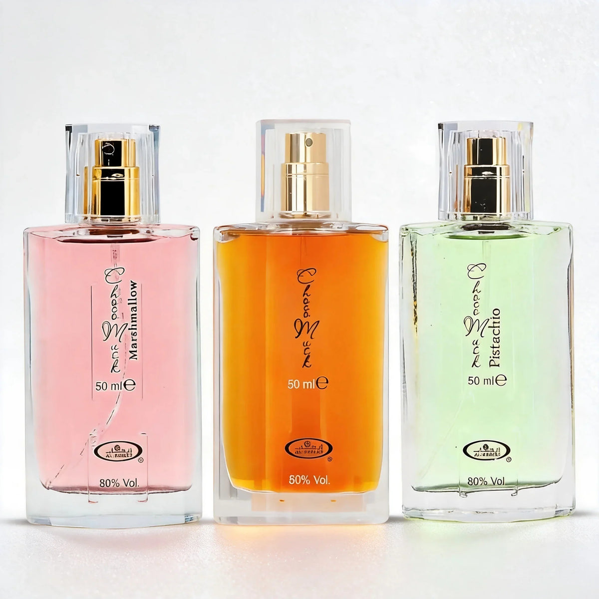 Three 50ml rectangular perfume bottles with gold caps, showing pink, amber, and light green liquid against a white backdrop.