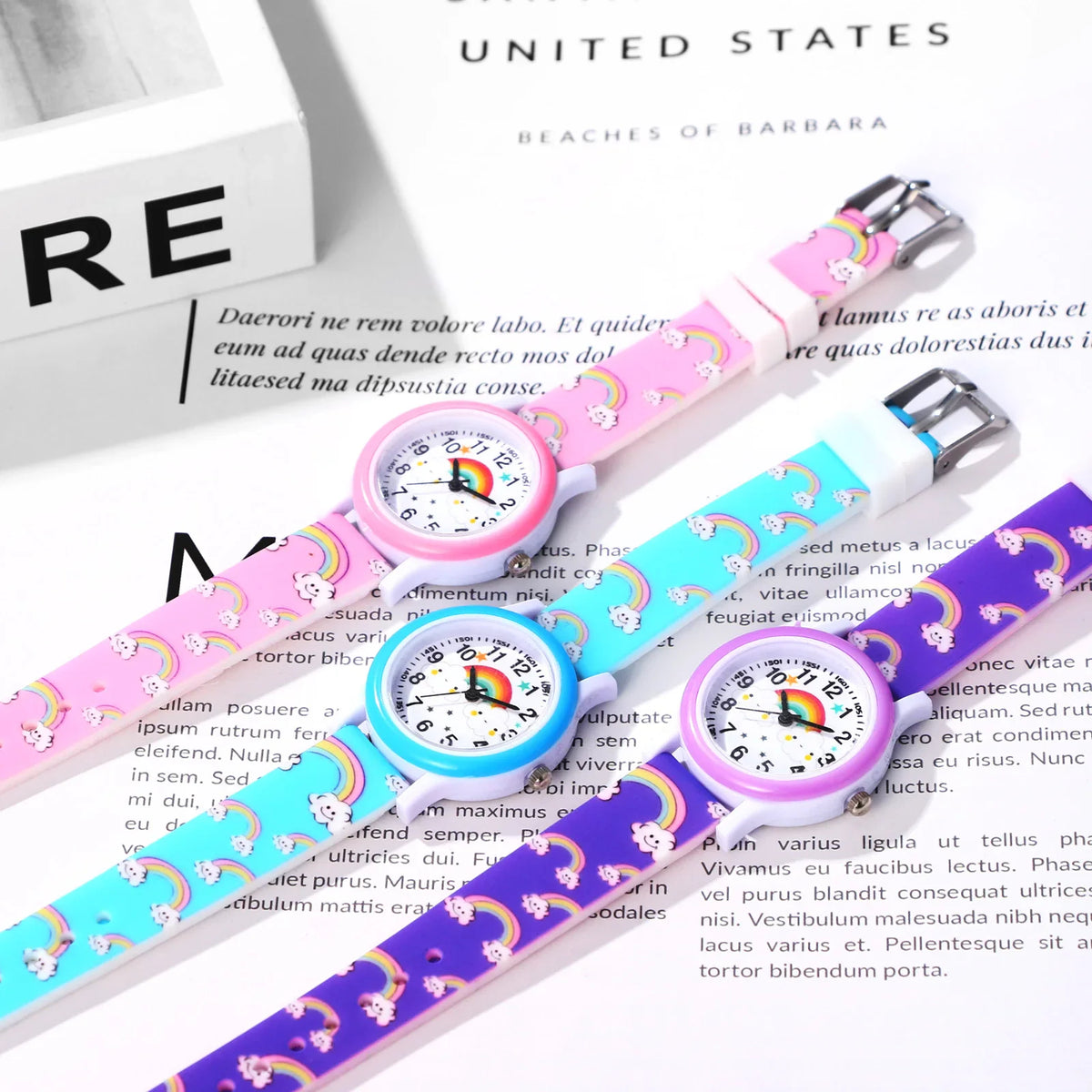 Three children's watches with rainbow and cloud print on silicone straps in pink, blue, and purple