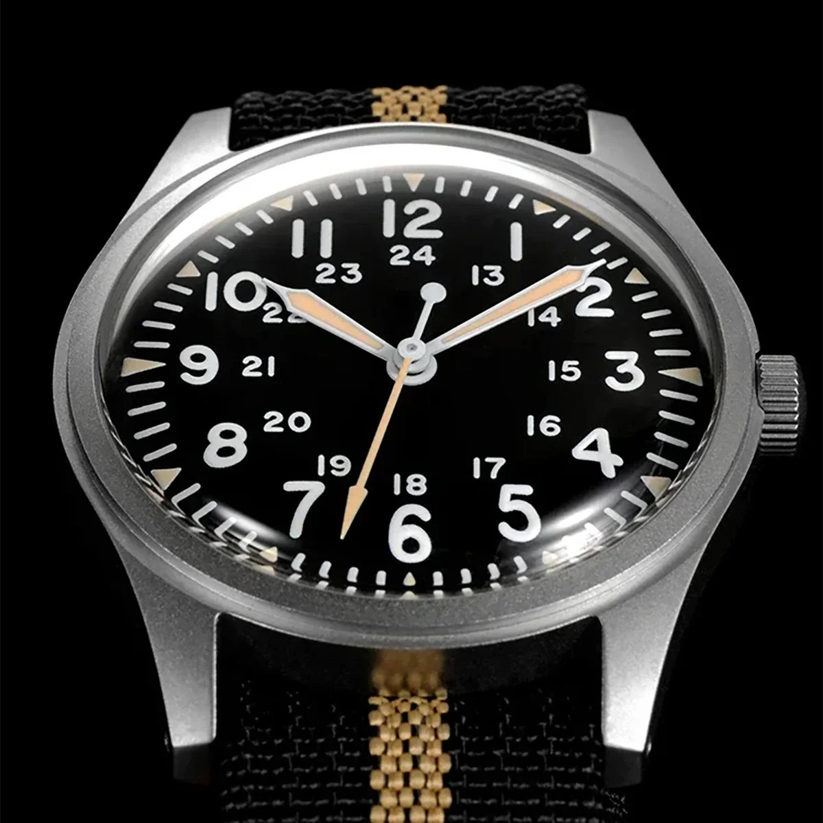 Close up of a men's military field watch with black dial and beige and black striped nylon strap
