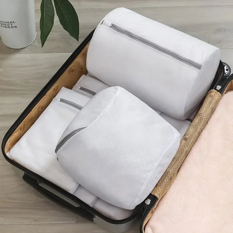 Cylindrical mesh laundry bags packed inside an open suitcase.
