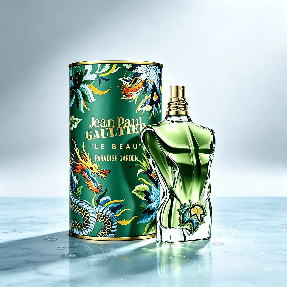 green torso shaped cologne bottle with an embroidered vine leaf, standing beside its matching decorative tin on a marble