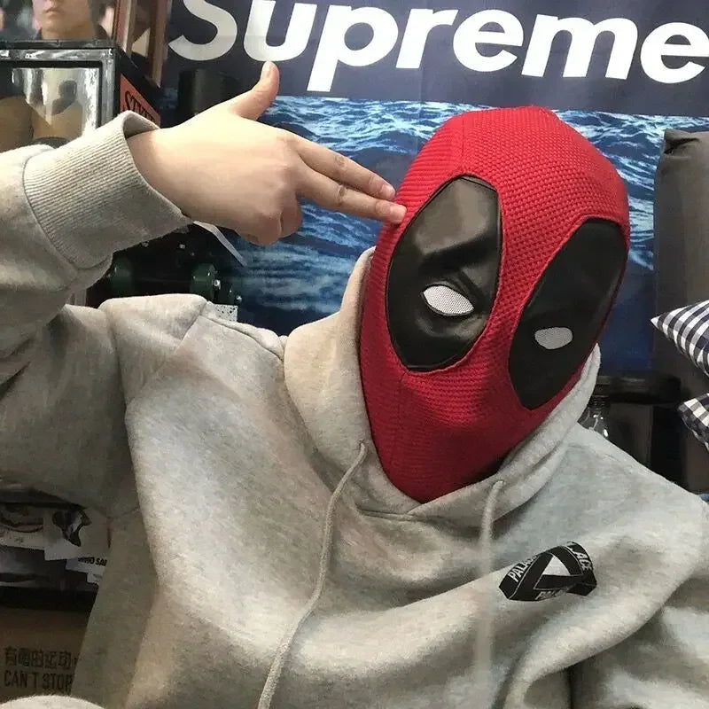 Person wearing a red and black knitted superhero mask with grey hoodie