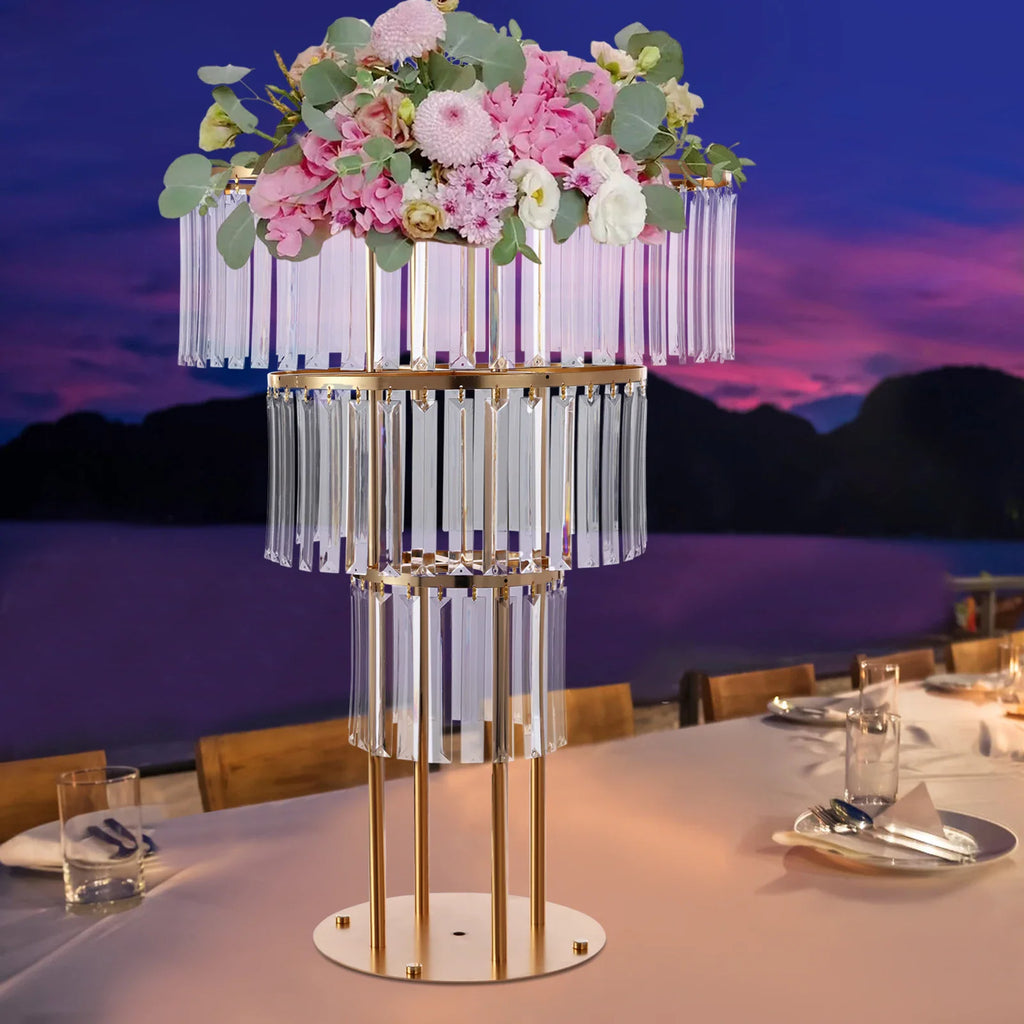 Three-tier gold crystal wedding stand set on a banquet table with a floral arrangement.