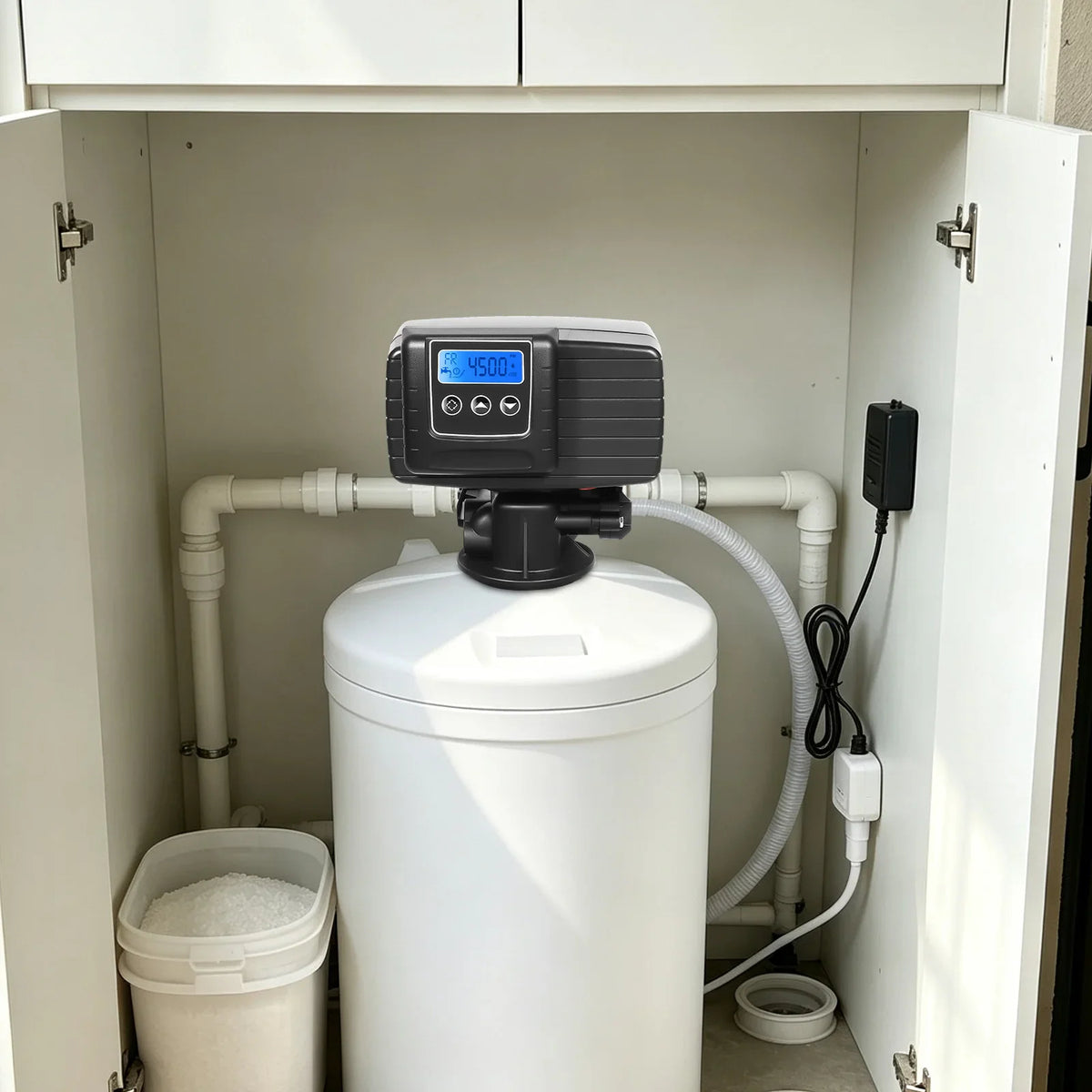 Digital water softener control valve installed on top of a white water treatment tank inside a cabinet