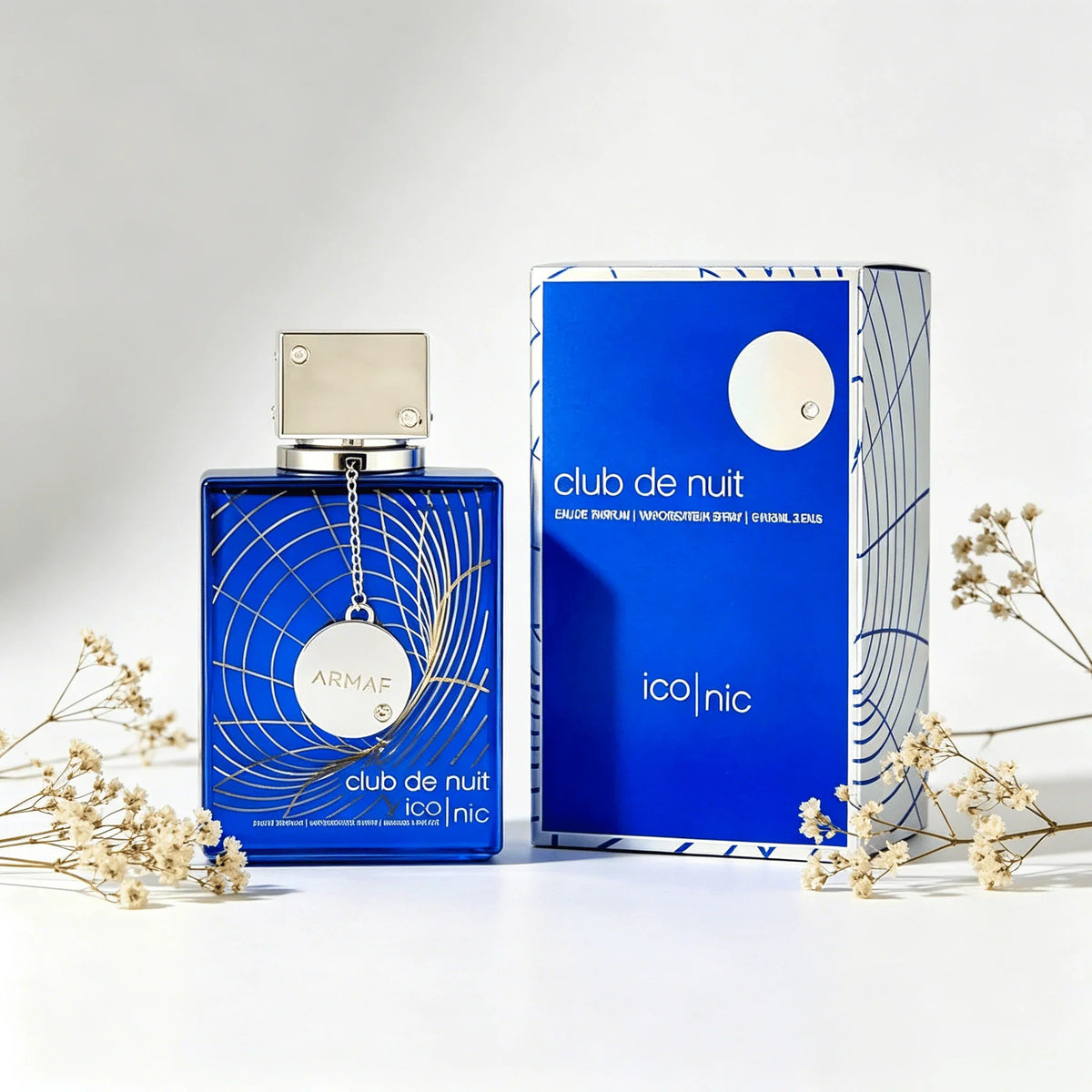 Blue perfume bottle and box arranged with small white dried flowers.