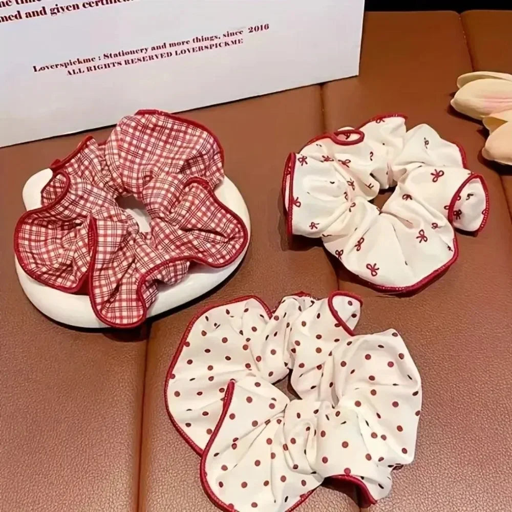 Three different red and white patterned hair scrunchies placed on a surface
