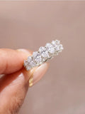 Eternity band ring featuring oval-cut white zircon stones set in sterling silver, worn on a finger.