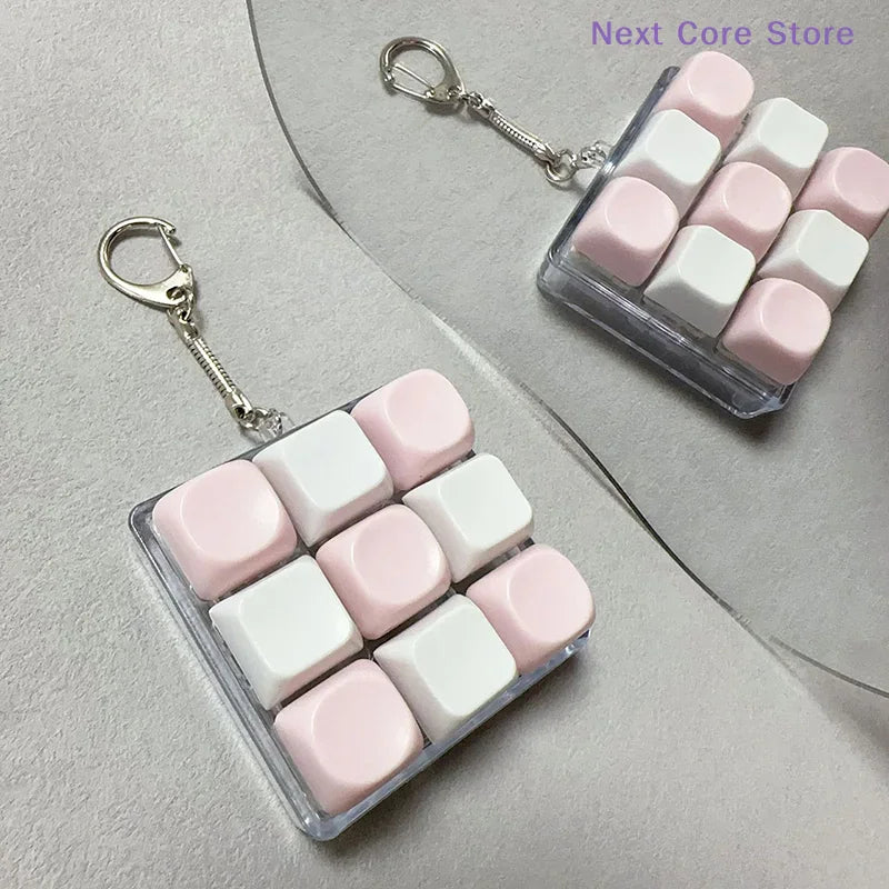A pink and white 9-key keyboard fidget keychain for stress relief