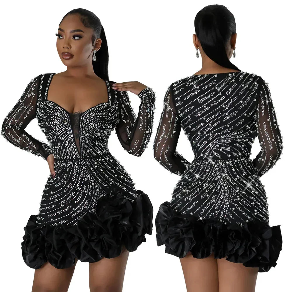 Front and back view of a black long-sleeved mini dress with pearl and crystal embellishments and a ruffled hem.