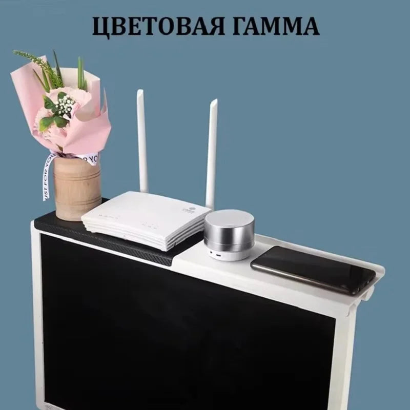 Adjustable screen top storage shelf holding a Wi-Fi router, speaker, smartphone, and a small bouquet of flowers