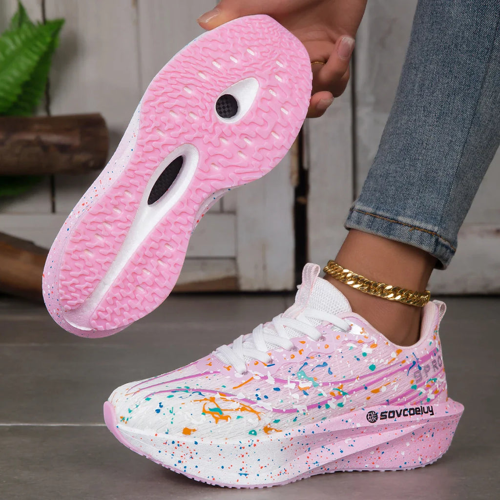 Pink and white paint splatter sneakers with a thick sole showing the treaded outsole