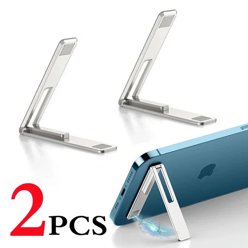 A pair of metallic ultra-thin foldable phone stands shown next to a smartphone with the stand attached.