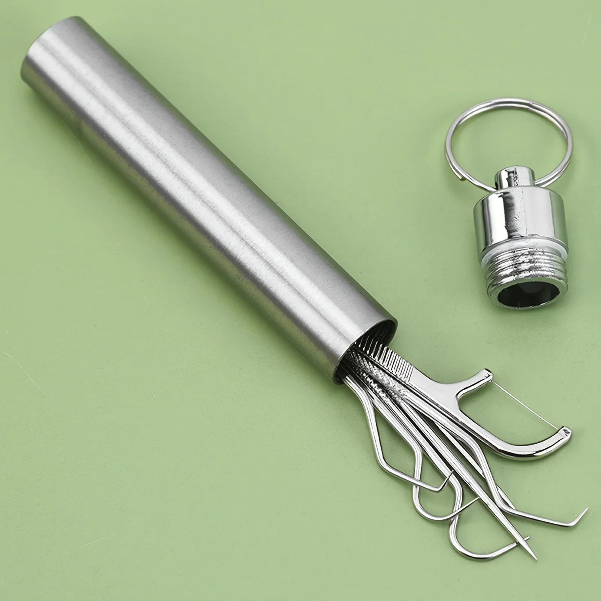 Reusable stainless steel metal toothpicks and floss picks being stored inside a cylindrical metal keychain container.