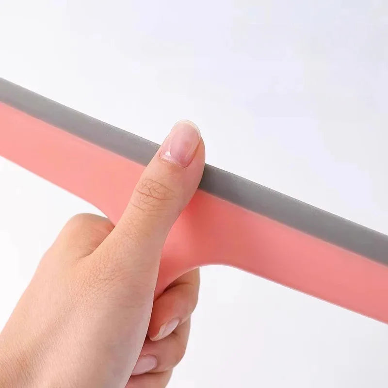 Hand holding the flexible silicone blade of a pink squeegee