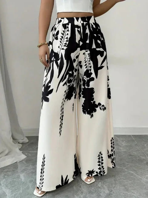 Woman wearing black and white floral print wide leg trousers with a plain white crop top