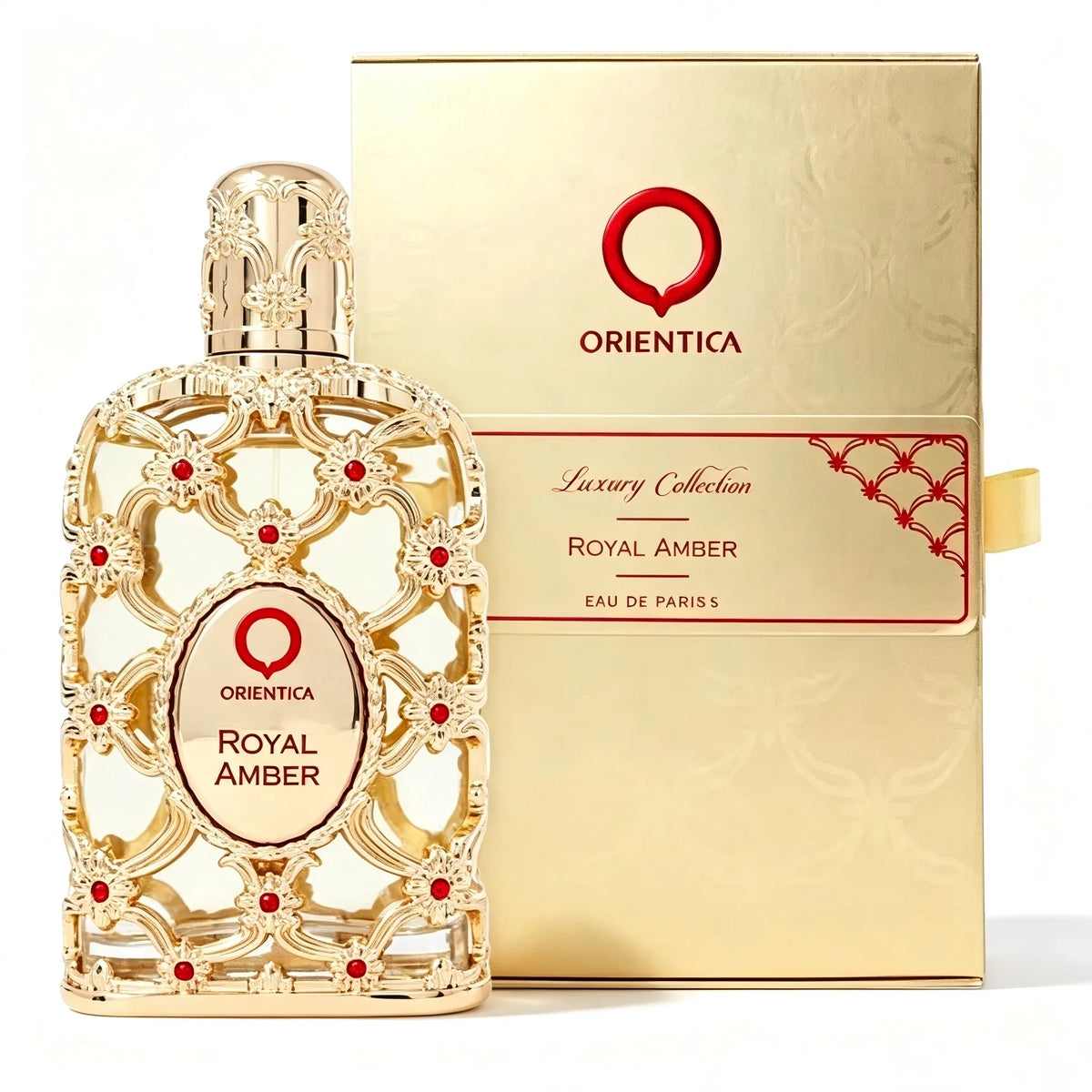 An ornate gold perfume bottle with red accents next to its matching gold retail box.