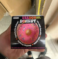 A hand holding a pink squishy donut toy inside its packaging box.