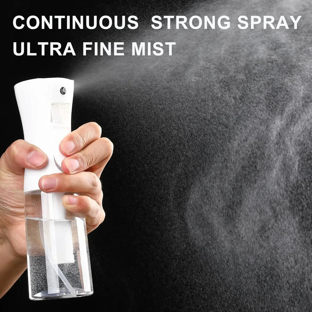 A white plastic continuous mist spray bottle being held and used to spray liquid