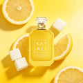 Bottle of lemon sugar scented perfume surrounded by lemon slices and sugar cubes on a yellow background