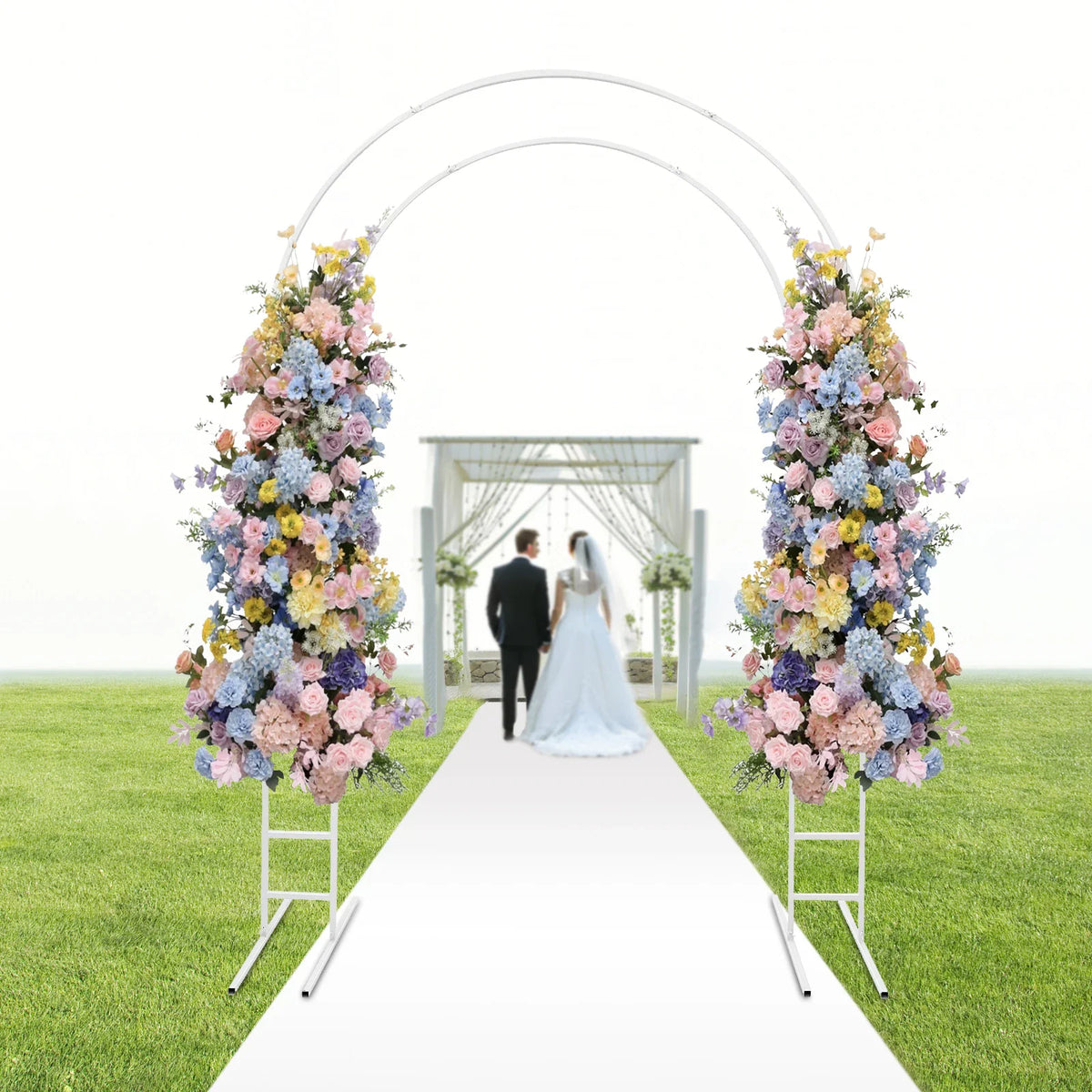 White metal round arch frame with pastel floral arrangements on a lawn wedding path