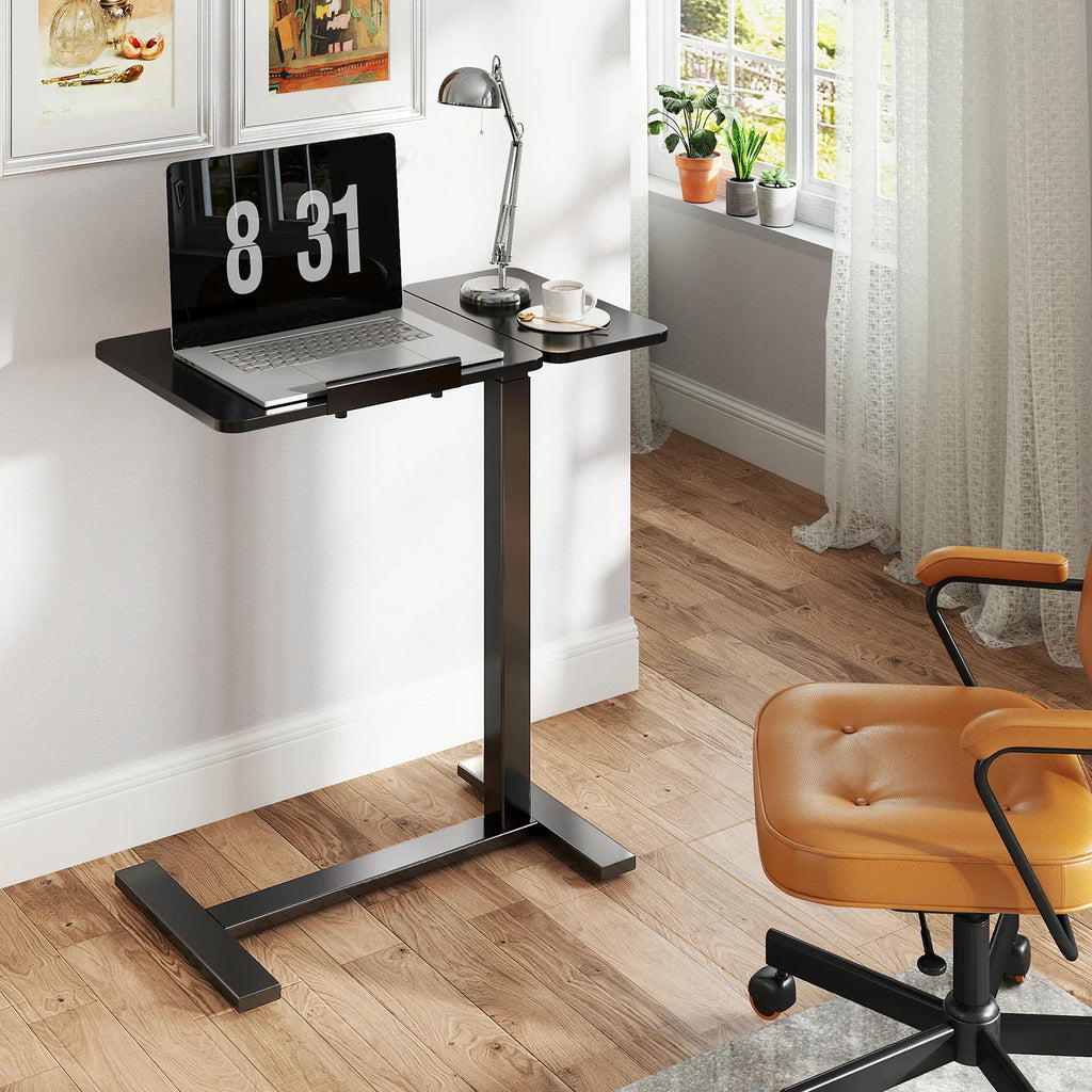 A black laptop desk with a laptop on it set up in a bright room beside an orange chair.