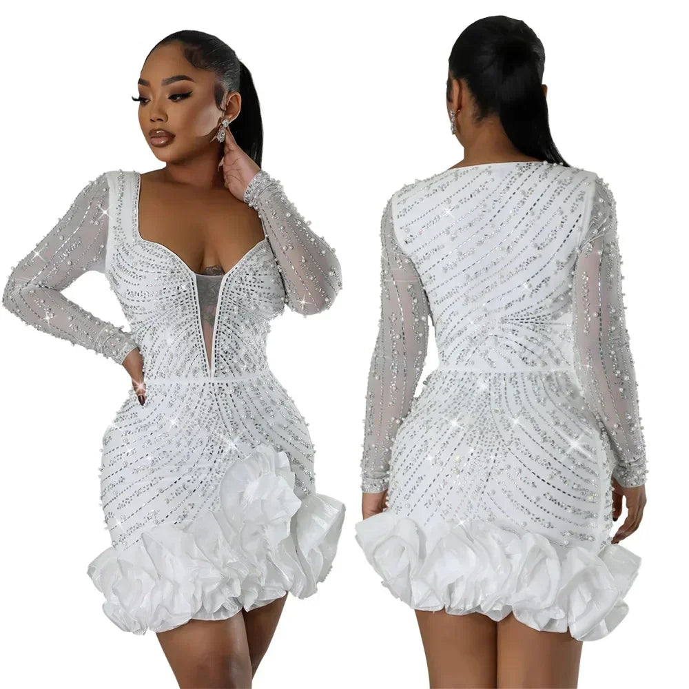 Front and back view of a white long-sleeved mini dress with pearl and crystal embellishments and a ruffled hem.