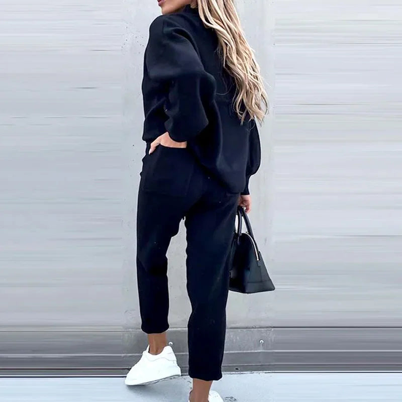 Back view of a woman wearing a black knitted two-piece set with a long sleeve pullover and jogger pants.
