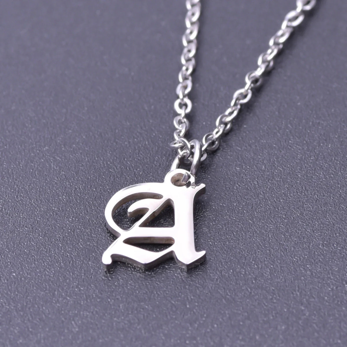 A single silver initial pendant necklace against a dark background