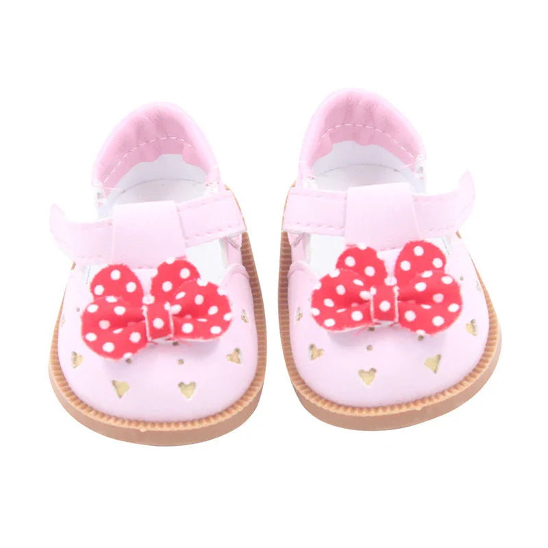 Pink doll shoes featuring cut-out hearts and a red polka-dot bow on the strap