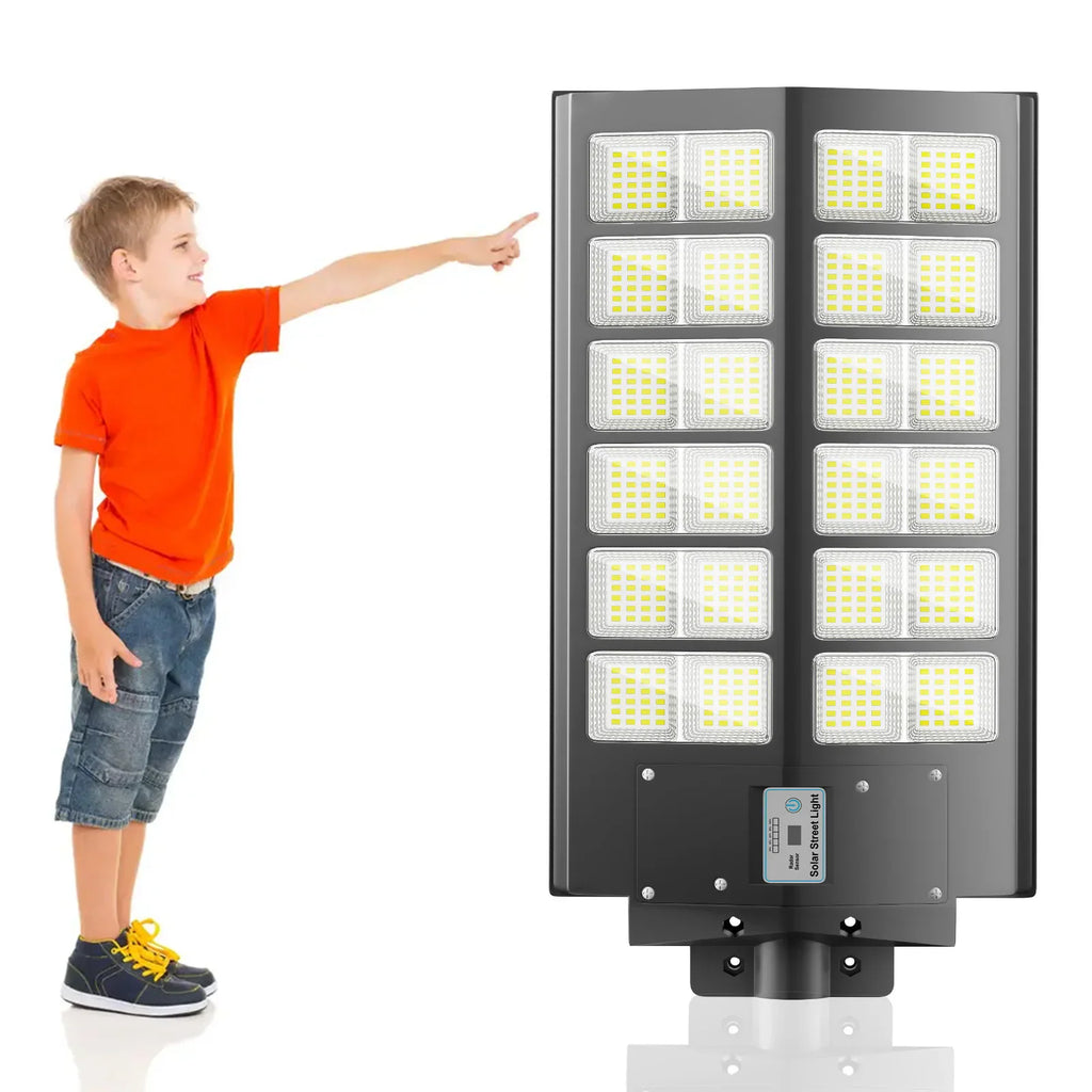 A young boy pointing at a mounted solar LED street light.