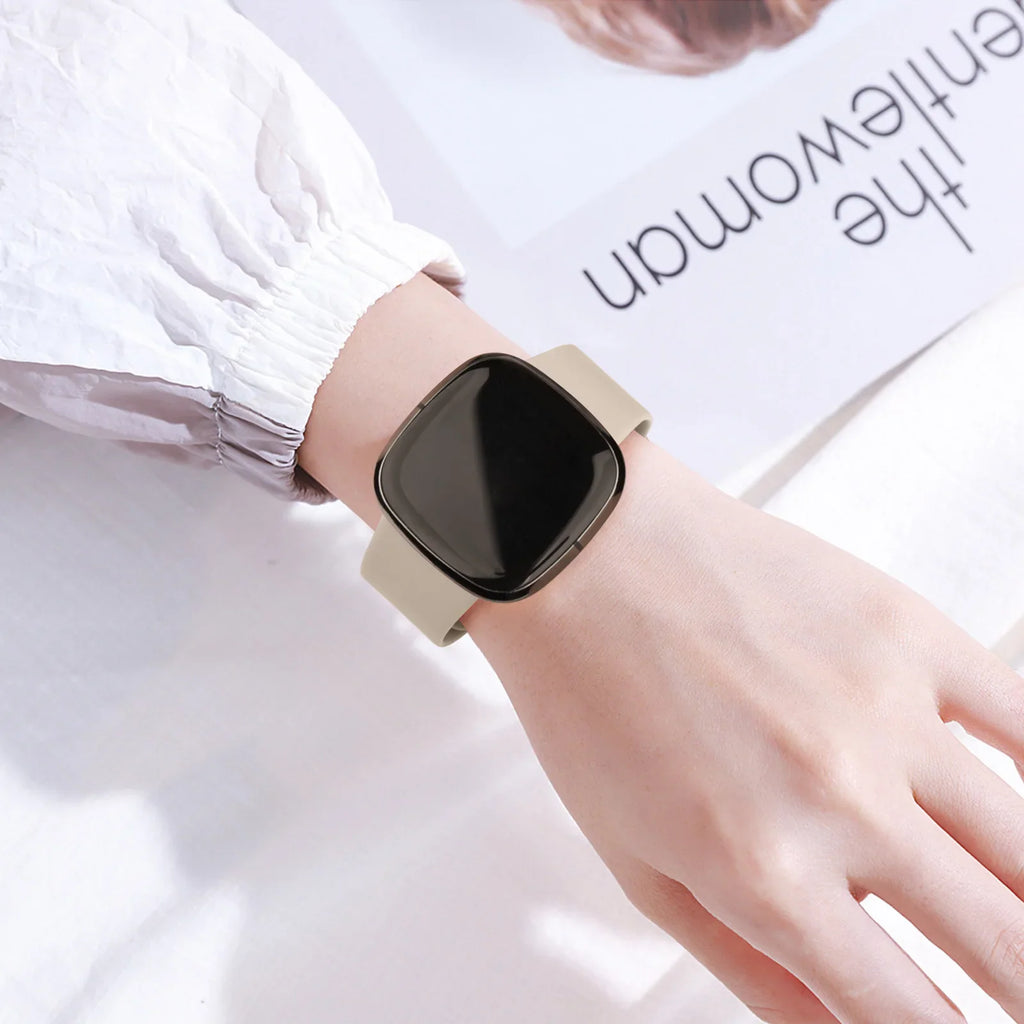 A person's wrist wearing a beige silicone smartwatch band.