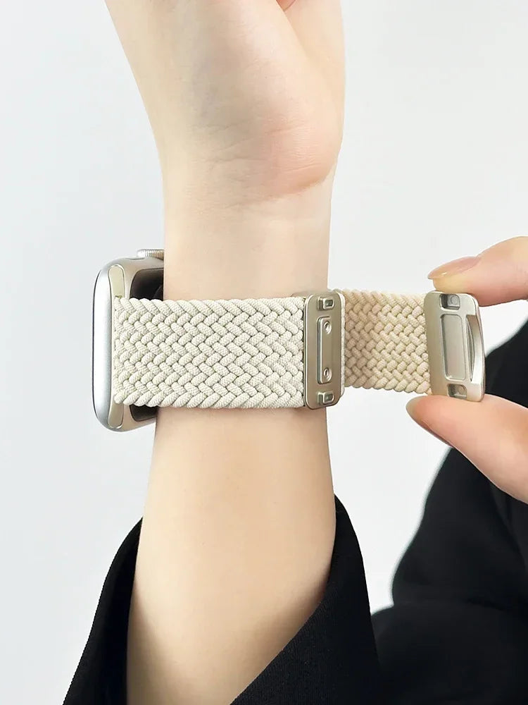 A beige braided watch band on a wrist, showing the adjustable magnetic clasp.