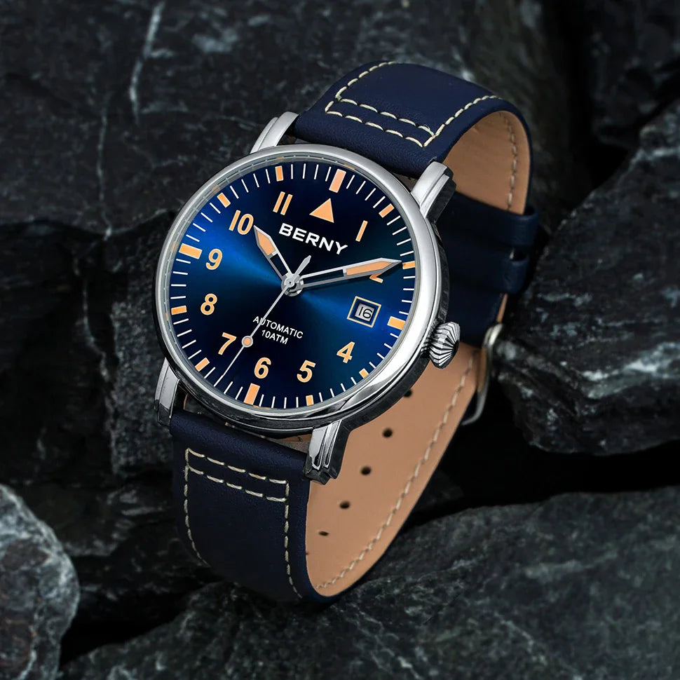 Blue dial automatic watch with leather strap displayed on textured dark rocks