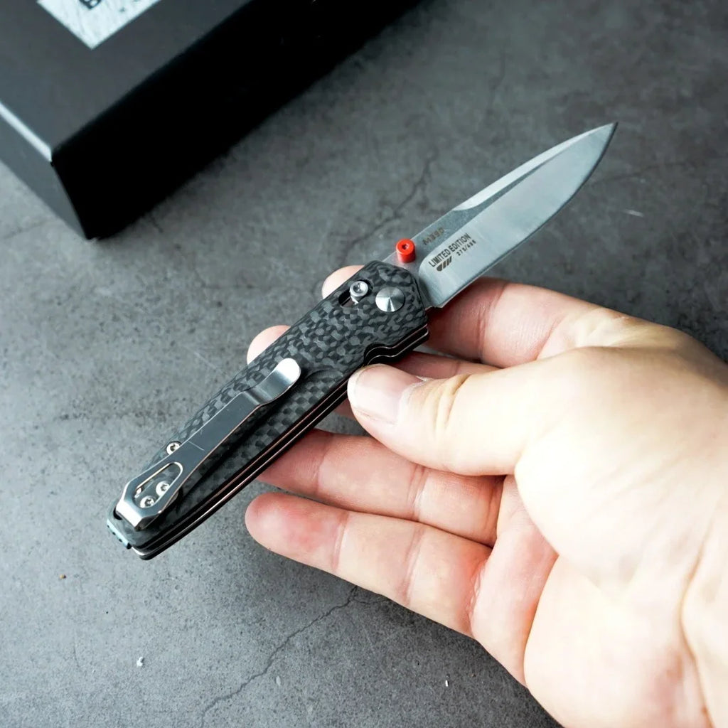 Tactical folding knife with a carbon fiber handle and M390 steel blade, held in hand
