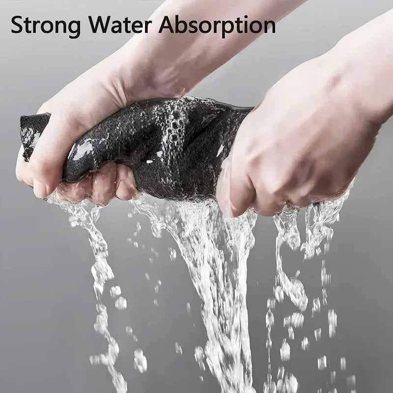 A hand wringing out a wet grey microfiber cleaning cloth over a sink.