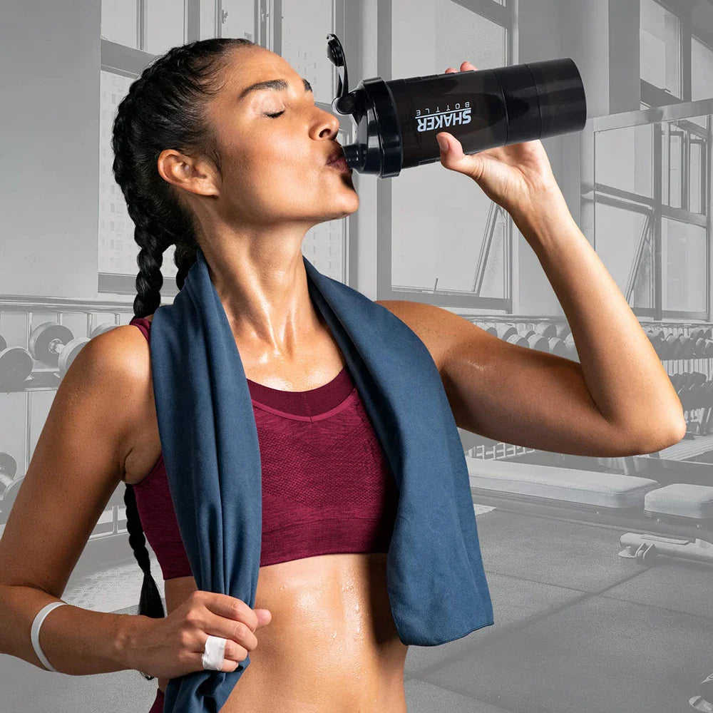 Woman at the gym drinking from a black protein shaker bottle