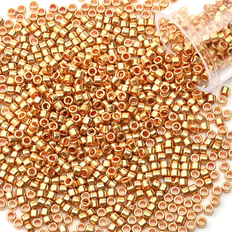 A pile of gold metallic glass seed beads next to a clear plastic container.
