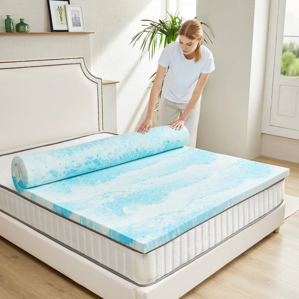 Person unrolling a blue and white gel memory foam mattress topper on a bed