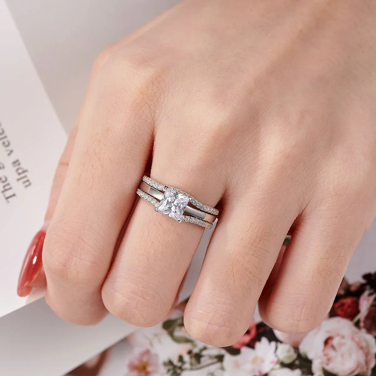 Princess cut sterling silver ring set worn on a finger.