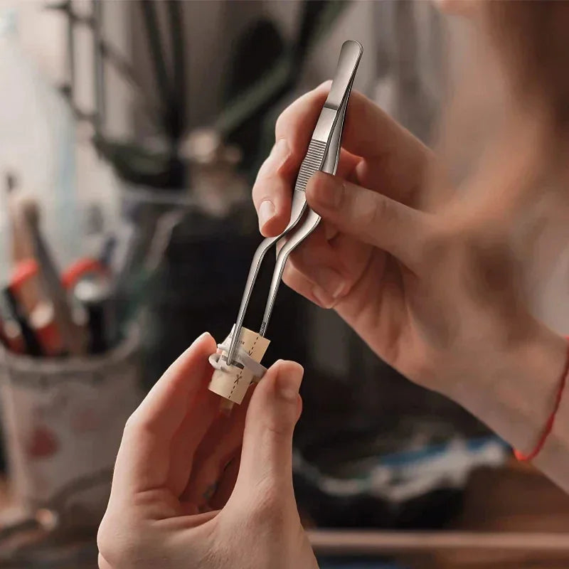 Hands using stainless steel precision tweezers to assemble a delicate craft item