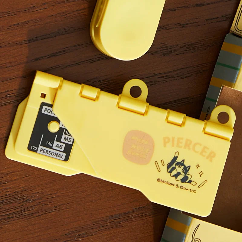 Close-up of a yellow portable mini hole puncher with a cute cat illustration.