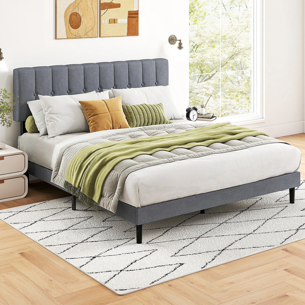 Grey upholstered button-tufted platform bed frame with modern decor in a bright bedroom