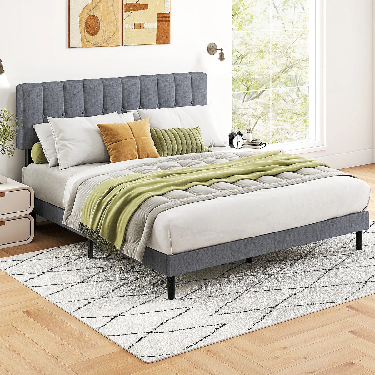 Grey upholstered button-tufted platform bed frame with modern decor in a bright bedroom