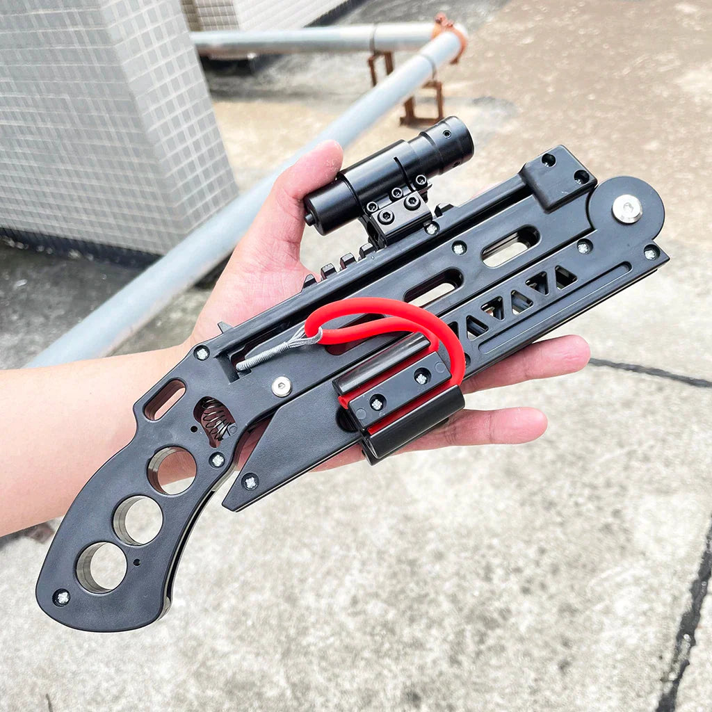 Black foldable slingshot with red elastic bands and mounted tactical sight held in hand