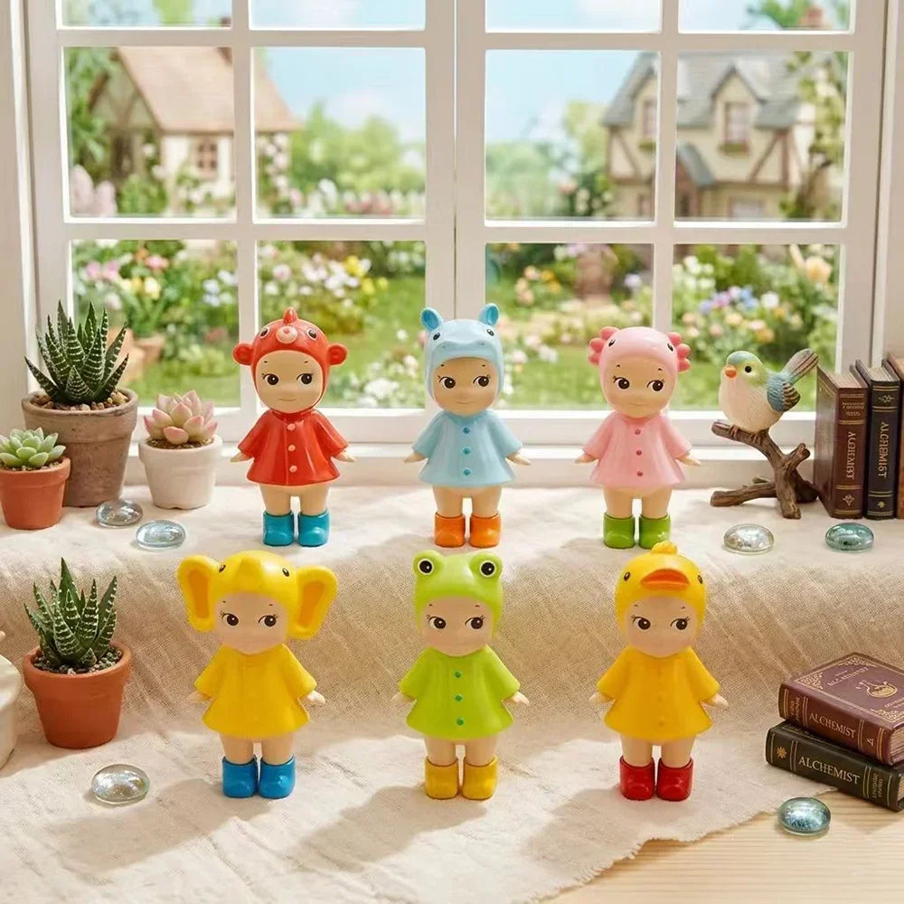 Group of six small collectible doll figurines in various animal hats and raincoats displayed on a windowsill
