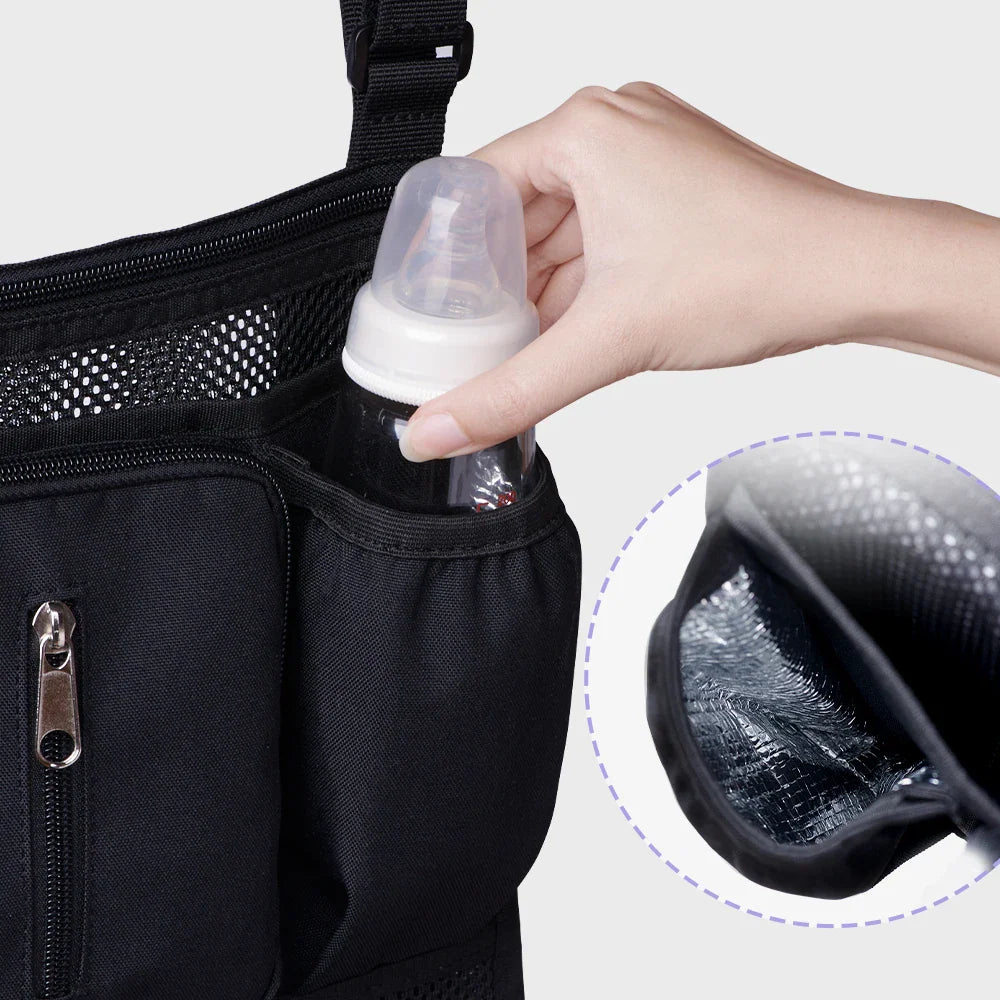 A hand placing a baby bottle into the insulated pocket of a black stroller organizer bag