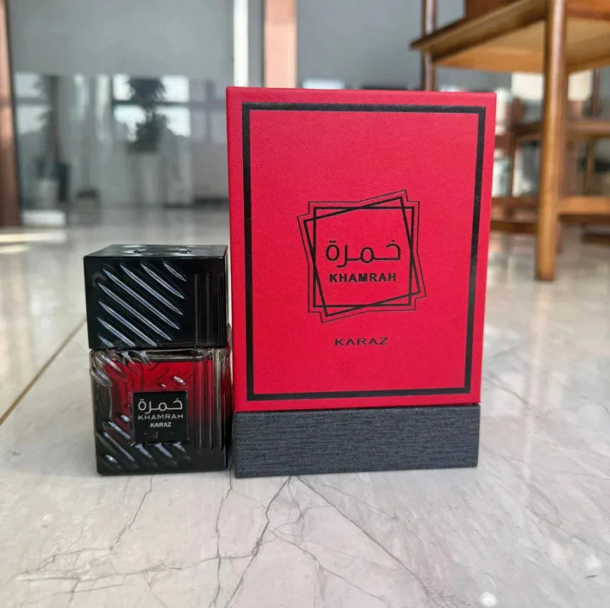 A perfume bottle and its red gift box set on a polished marble surface