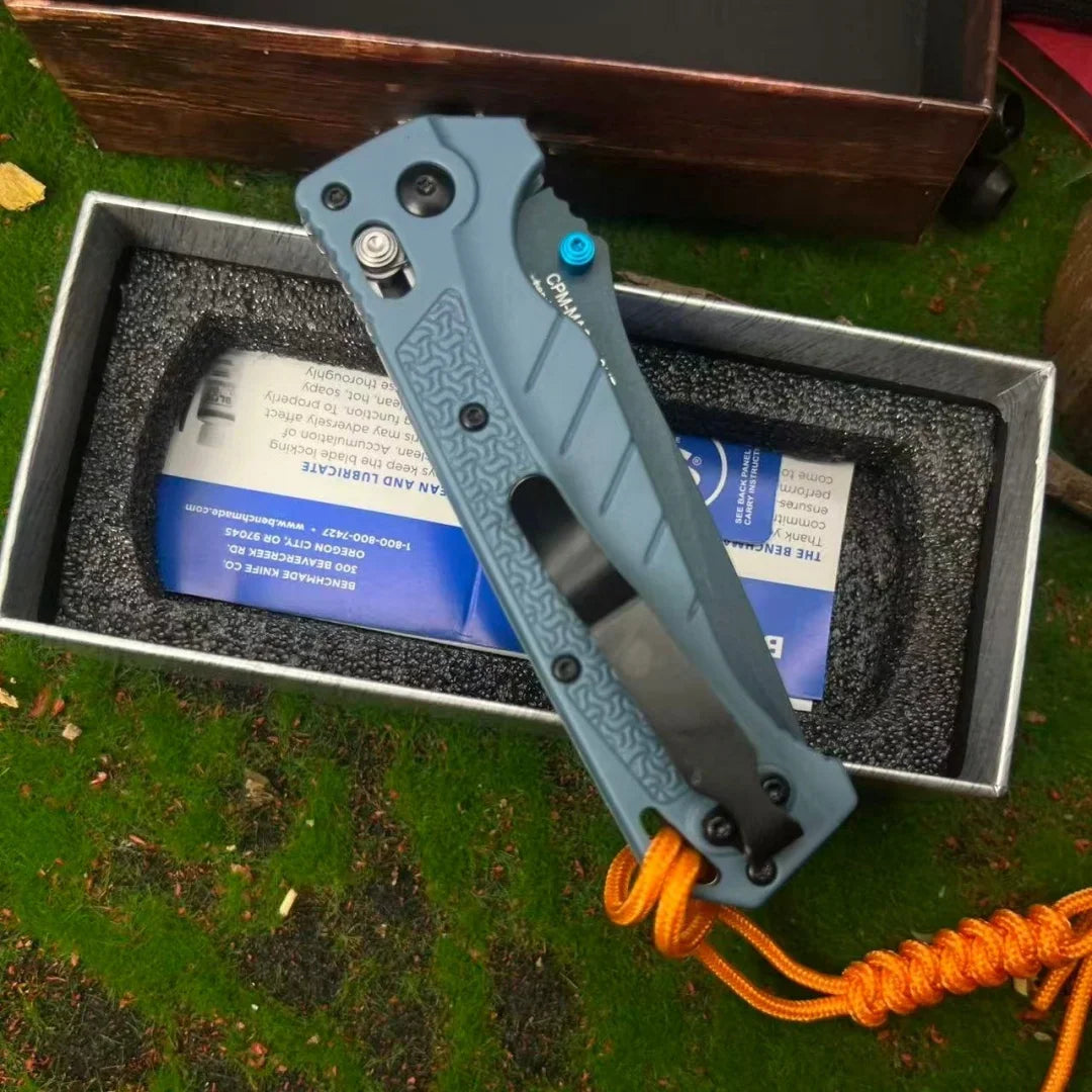 Grey folding pocket knife with a drop point blade and textured handle with an orange paracord lanyard