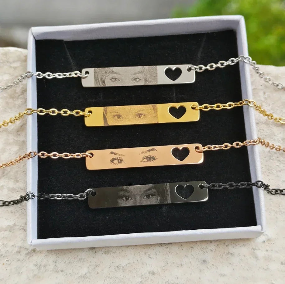 Four personalized photo engraved bar bracelets in silver, gold, rose gold, and black with heart cutouts, inside a gift box.