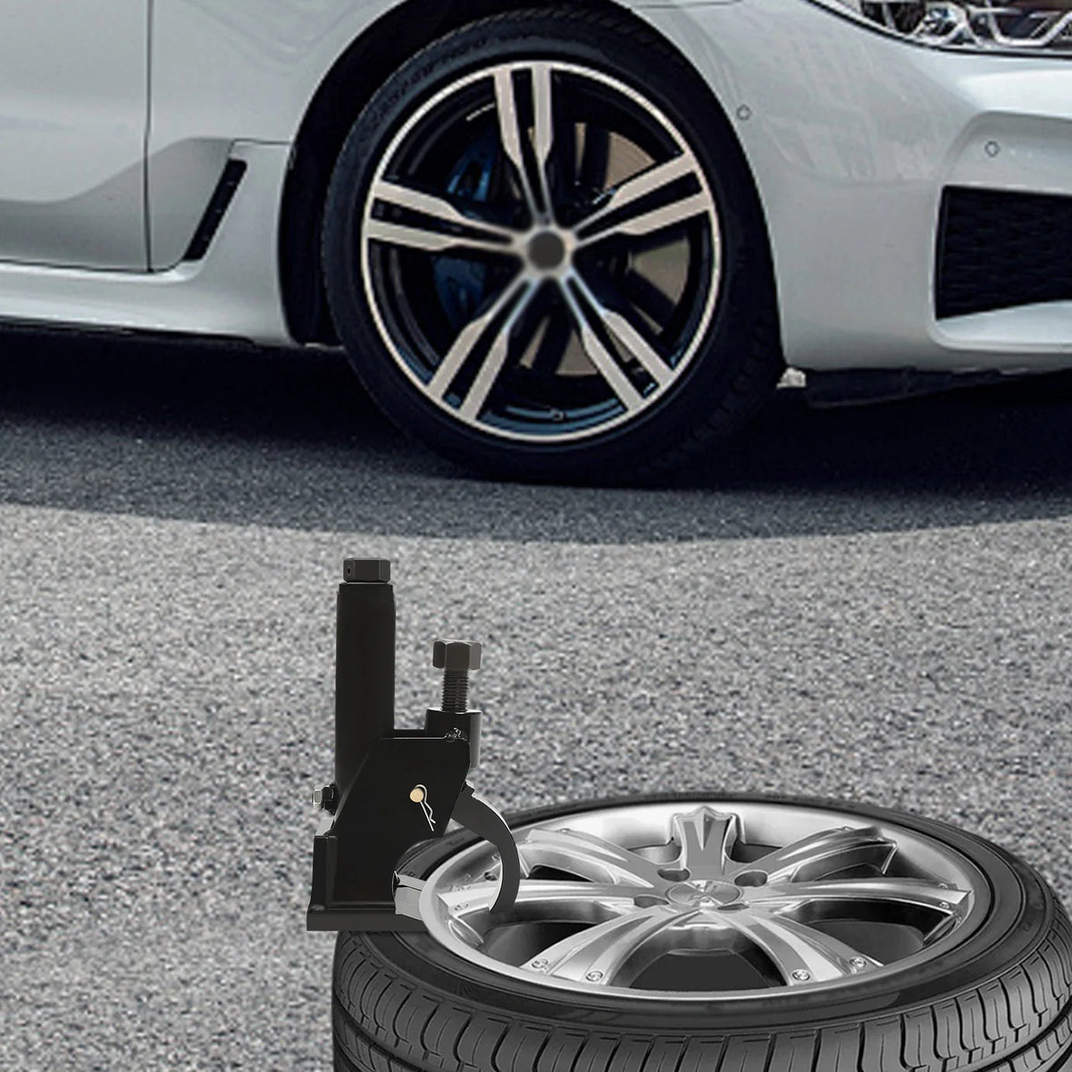 Black manual tire bead breaker tool being used on a car tire